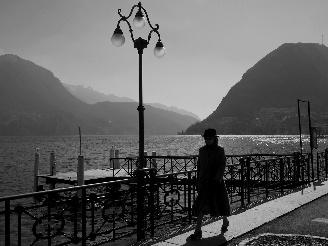 Быстрым шагом по набережной Lugano Lugano Лугано город Швейцария озеро Lago di горы дымка природа фонарь набережная женщина прогулка