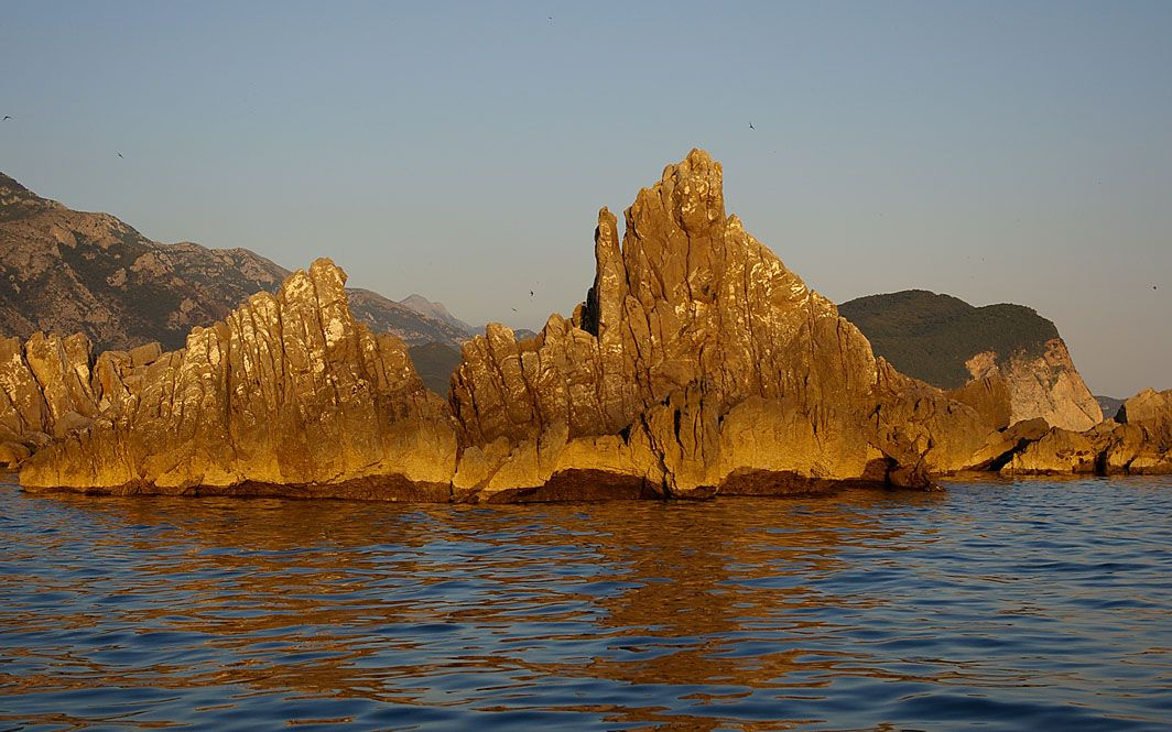 Разбивая волны, ветер, отражая солнце.. черногория море скала камни преграда закат