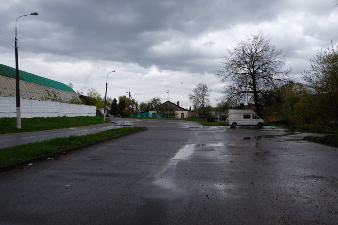 Низкая облачность асфальт лужи пасмурно столбы деревья строения небо облака автомобиль
