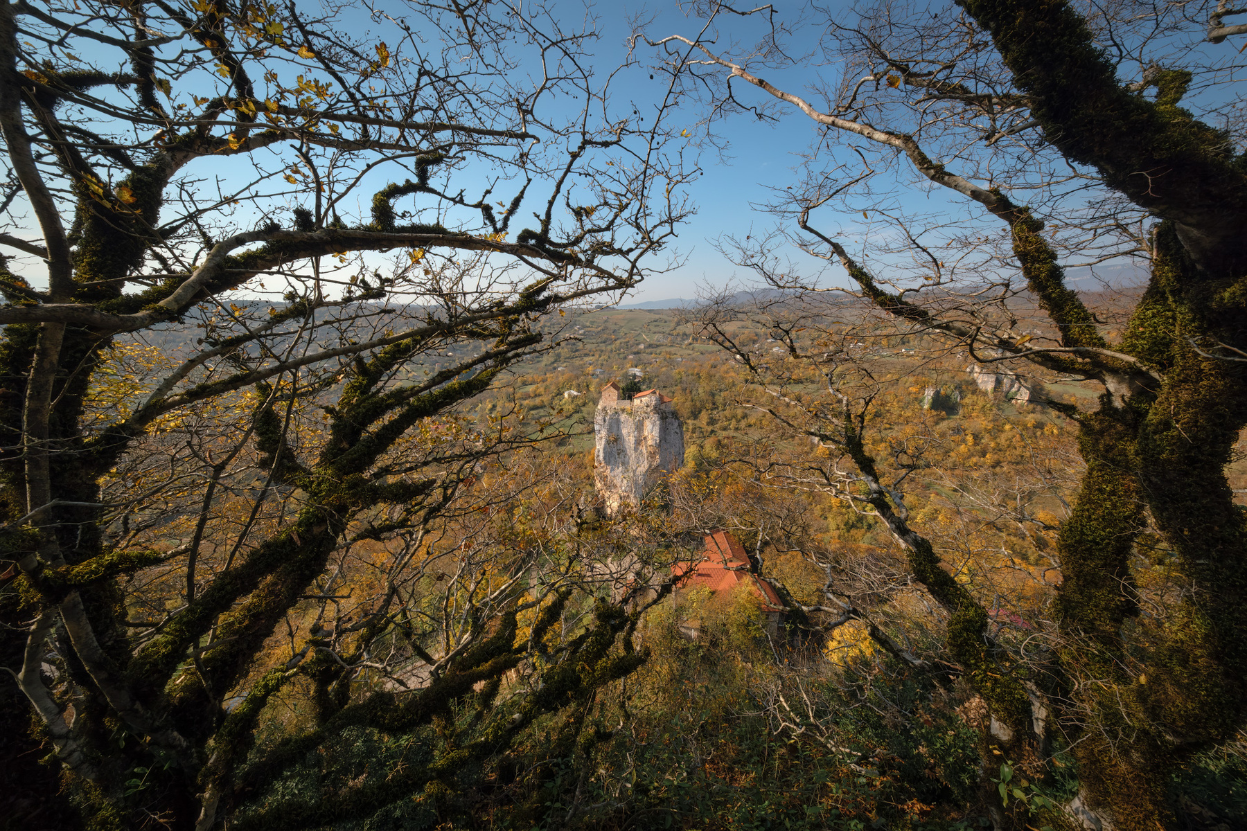 Katskhi Pillar View From Forest katskhi pillar imereti monastery fall autumn trees brunches mountains view landscape scenery travel outdoors georgia sakartvelo chizh